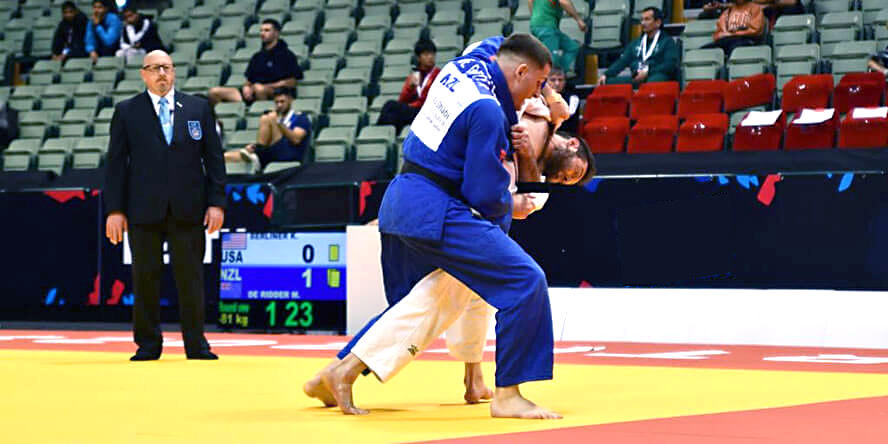 Kell Berliner, wearing white, overpowers an opponent whose face is obscured.
