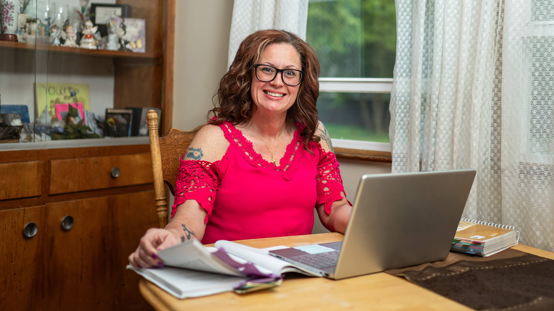 Shields is sitting at a desk in her home with a laptop computer open.