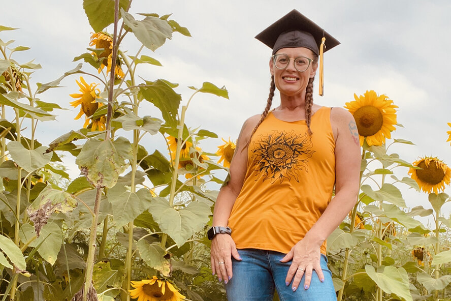 Shields is standing among sunflowers with her graduation cap on.