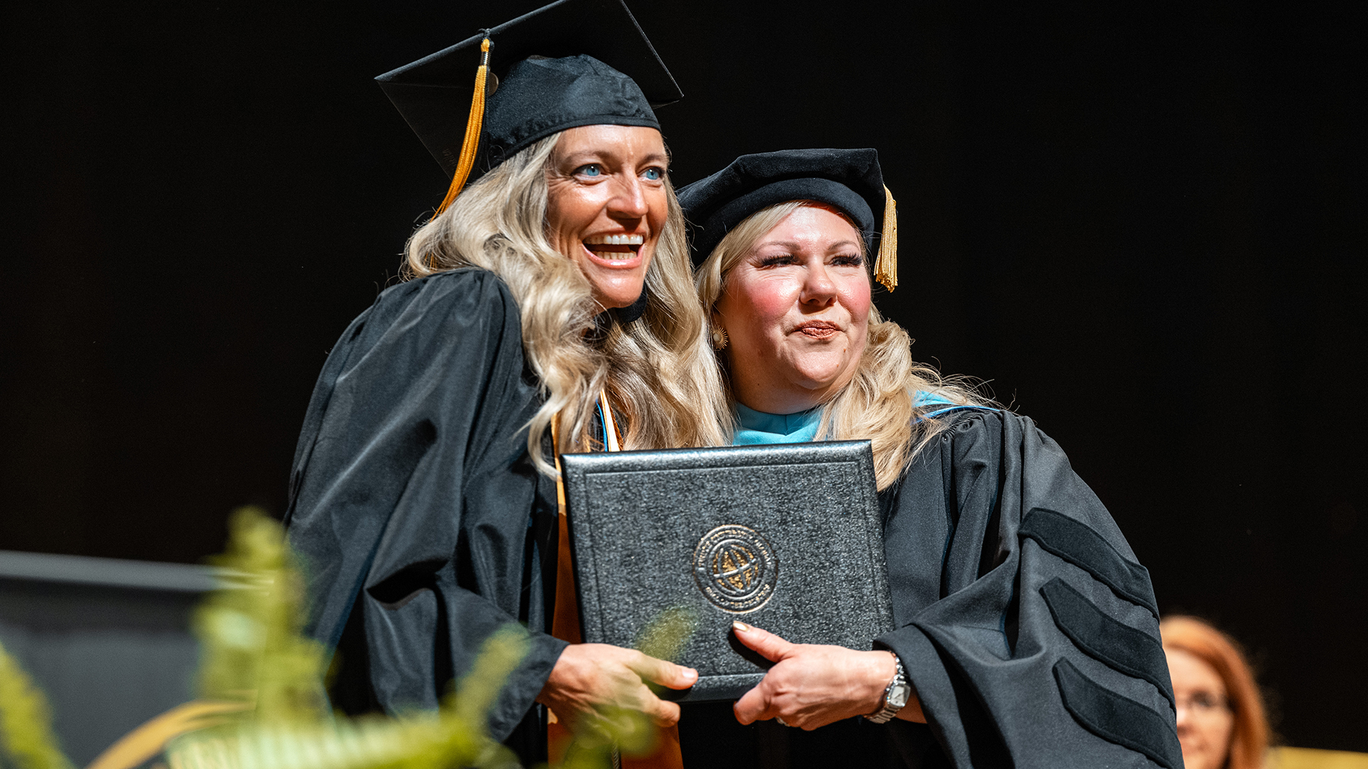 Leighellen in her cap and gown on stage accepted her Purdue Global degree.