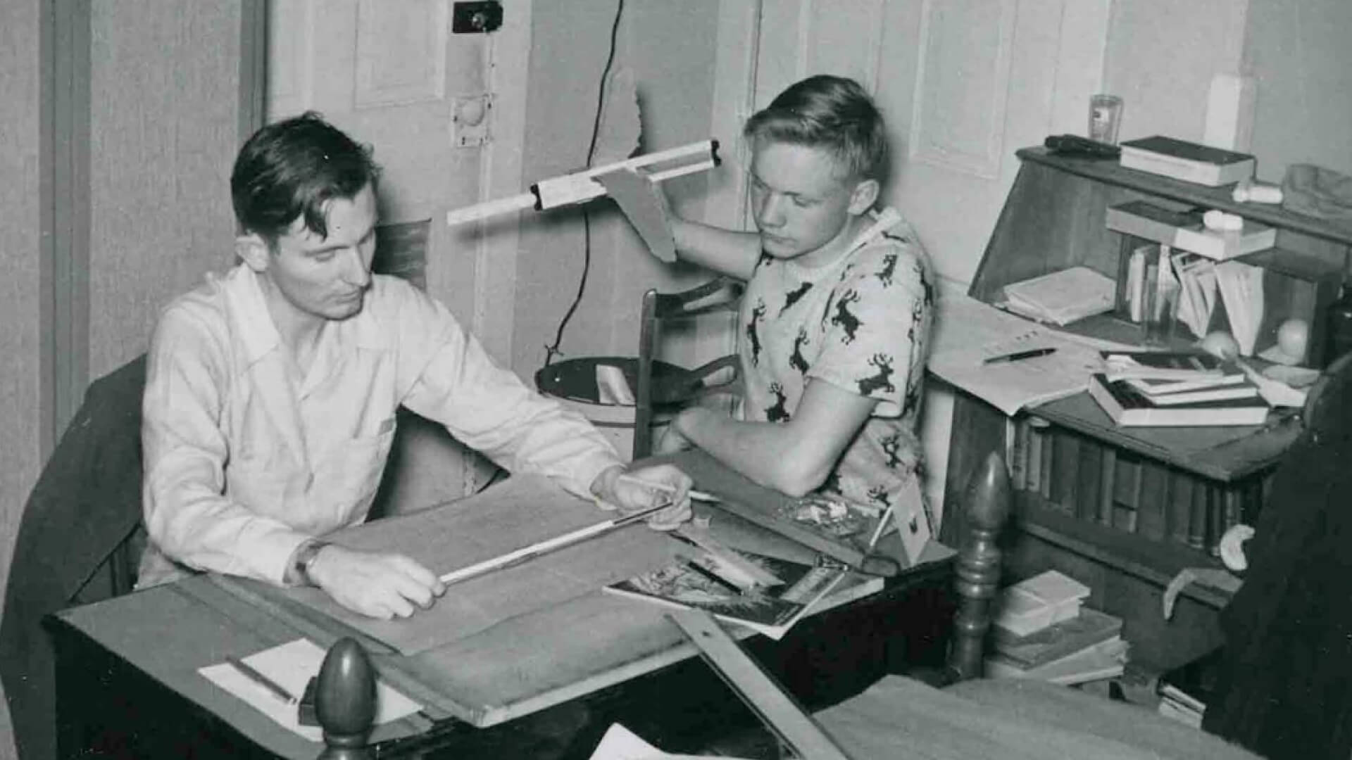 Purdue student Neil Armstrong holds up a model airplane while studying with a classmate