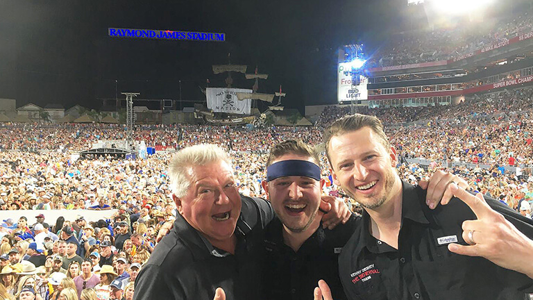 Jonathan Bailey with two other crew members in a concert arena.