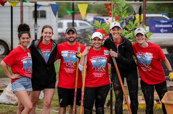 Kara Allen poses with a group of volunteers in her community, holding a garden tool.