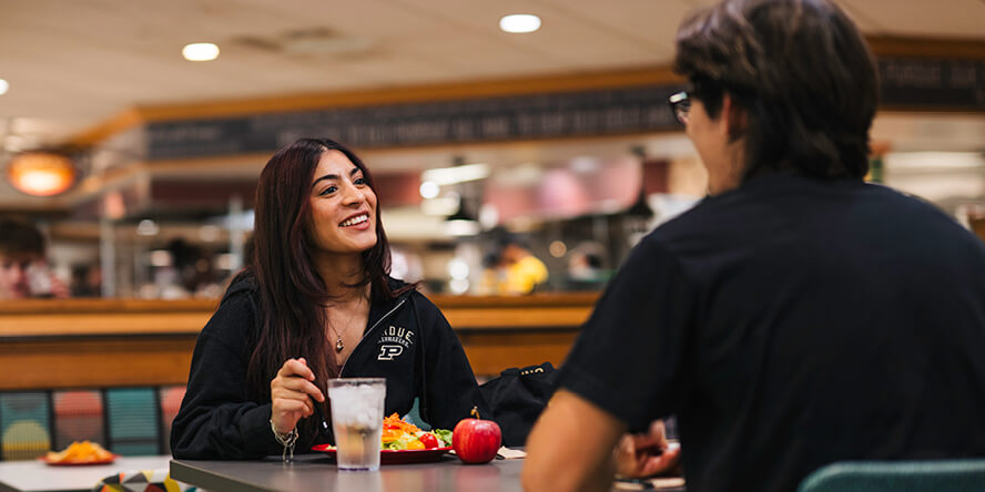 Prasad sits across from a friend at a table in Windsor Dining Court.