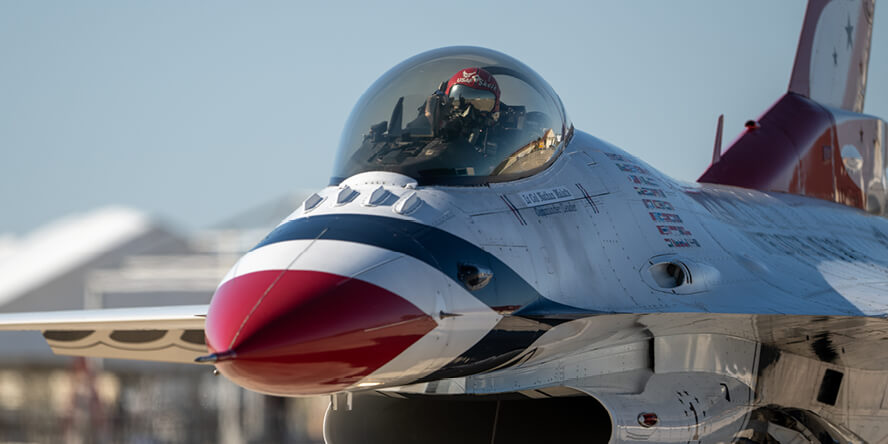 A pilot in a jet on a tarmac.