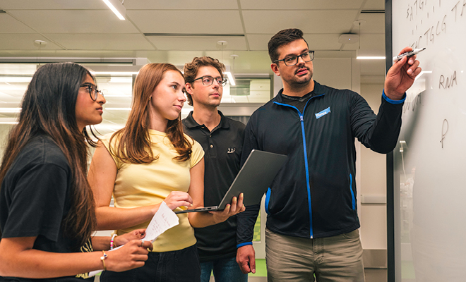 Purdue and Elanco collaborators review notes and brainstorm together at a whiteboard.