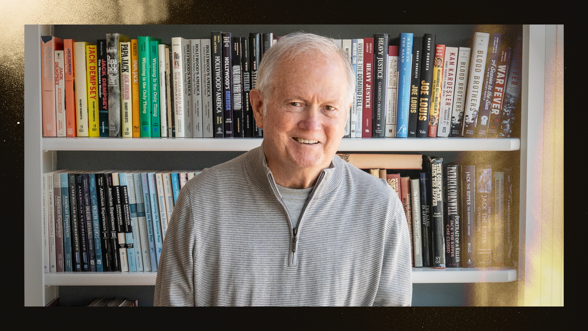 Purdue history professor Randy Roberts stands in front of a bookshelf that contains many of his books on sports history