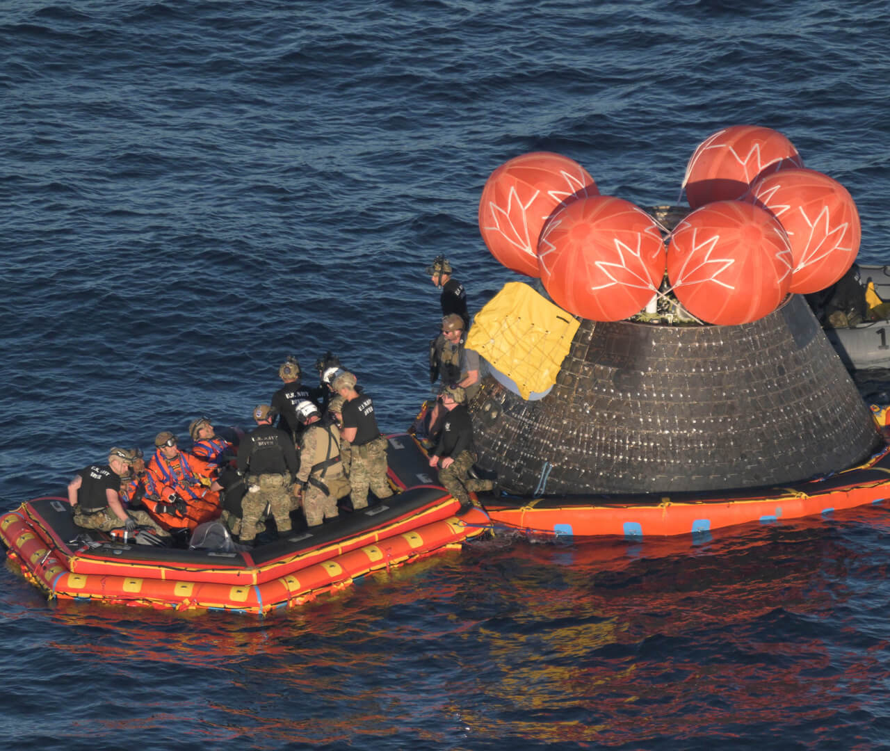 The recovery team practices helping astronauts exit the crew module onto an inflatable floating platform