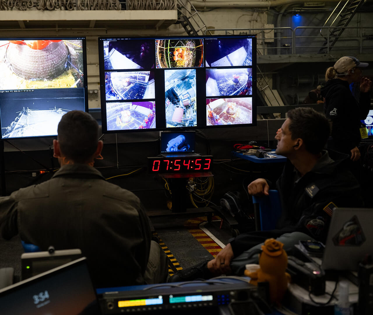 The Artemis crew module floats into the well deck of a Navy ship during a training session