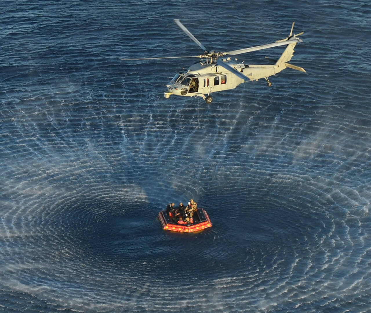 A recovery helicopter practices transporting astronauts from the ocean to a Navy ship during a training session