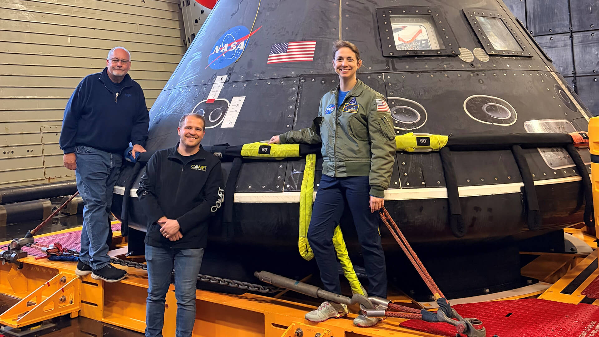 Purdue alumni Rob Lantz, Jason Endsley and Emily Spreen stand next to a practice Orion crew module