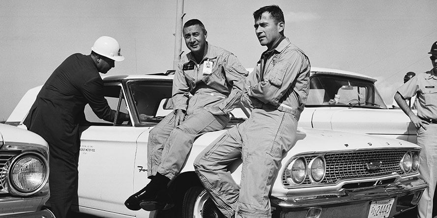 Astronauts Gus Grissom and John Young sit on a car