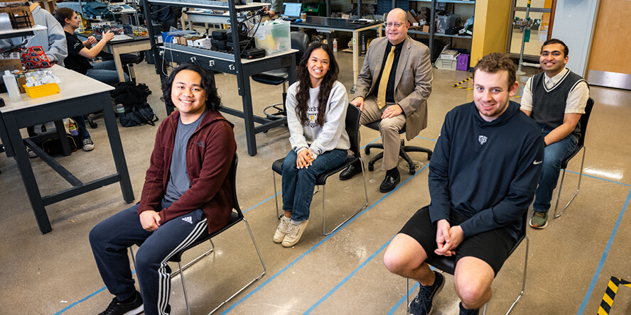 Steven Collicott, Abigail Mizzi and three student assistants sit in chairs lined up to approximate where the five crew members will sit during the Purdue 1 mission