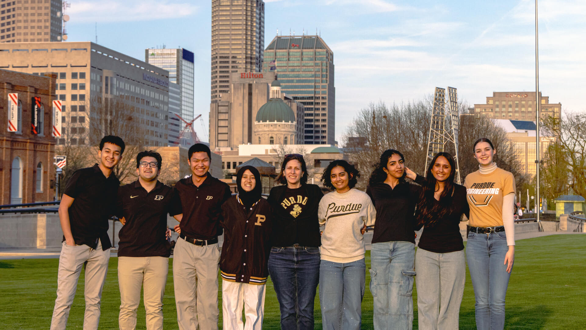 Sharon Miller poses with a group of students in Purdue gear with the Indianapolis skyline in the background.