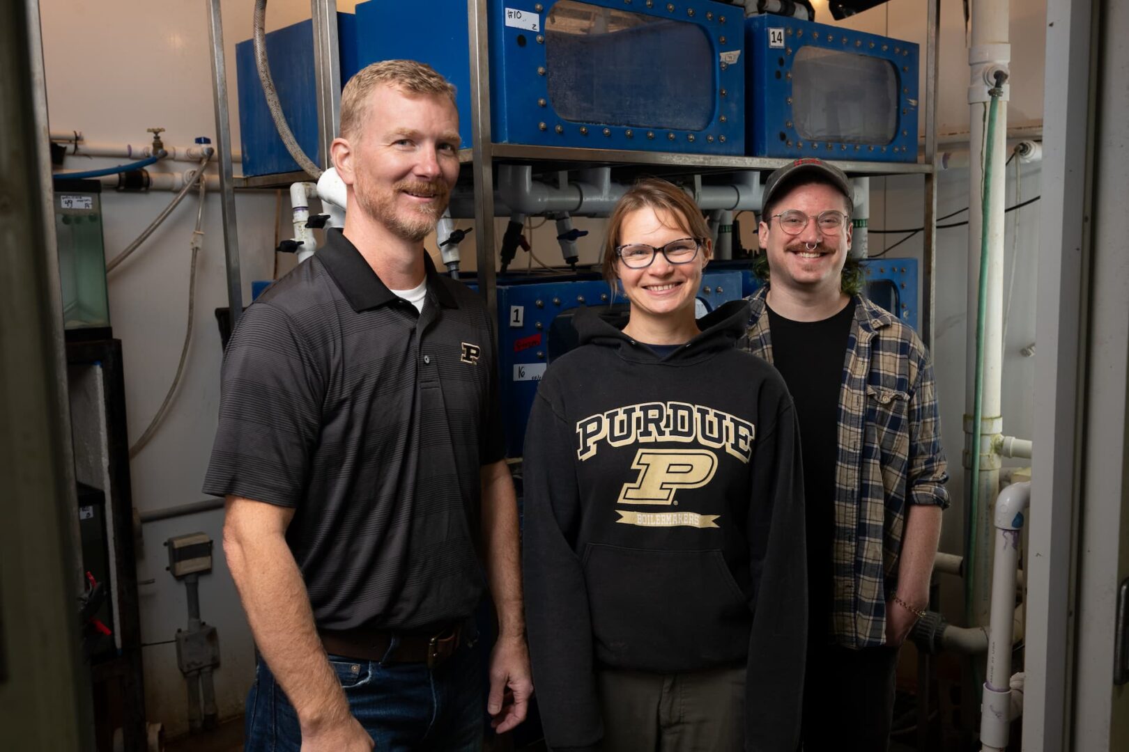Three Purdue hellbender salamander researchers pose in their lab. 