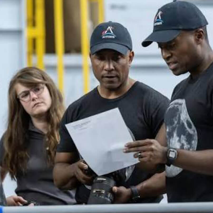 Marie Henderson looks on as a pair of colleagues review a document  
