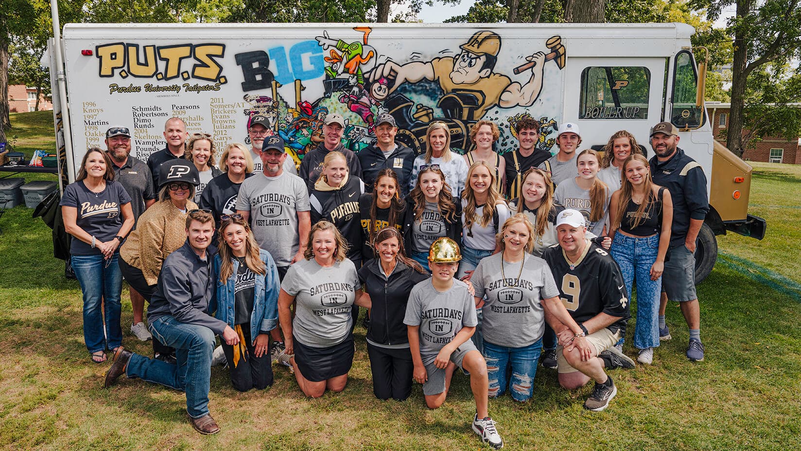 A group of Purdue football fans in front of their vehicle used for tailgates.