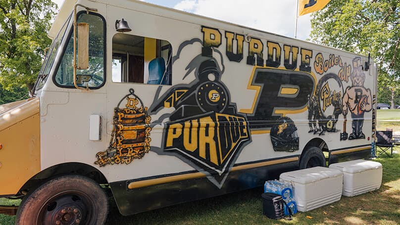 The driver side of a bread truck that has been painted with references to Purdue.