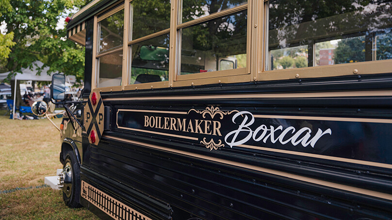 Toward the middle of the bus, the phrase “Boilermaker Boxcar” is painted.