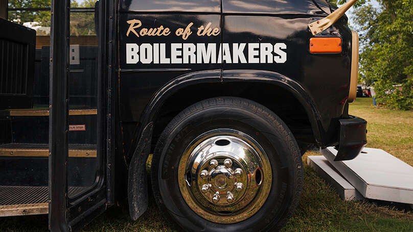 Toward the front of the bus, the phrase “Route of the Boilermakers” is painted.