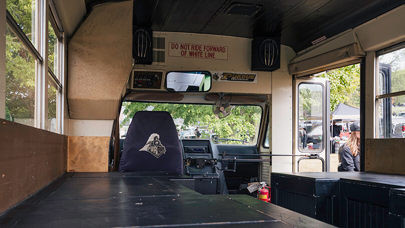 The inside of the bus, where the driver’s seat has a Purdue cover.