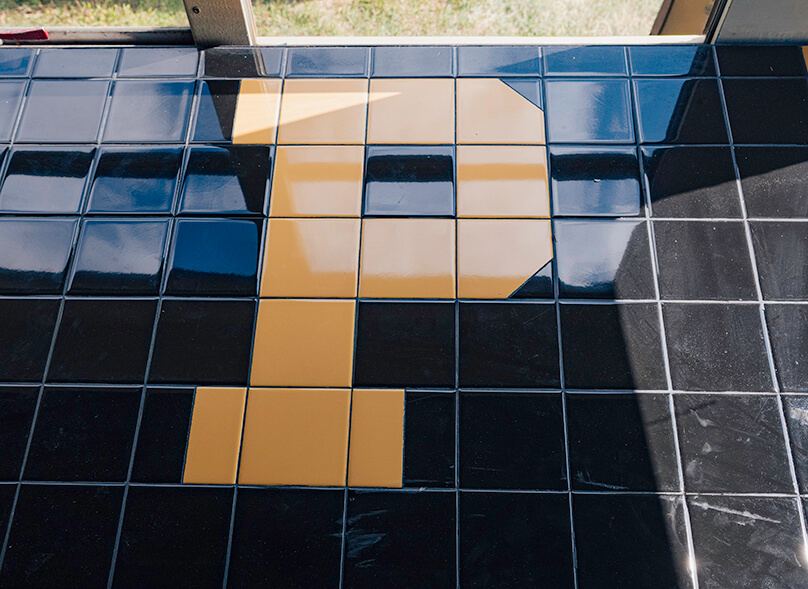 Black and gold tiles forming a letter “P.”