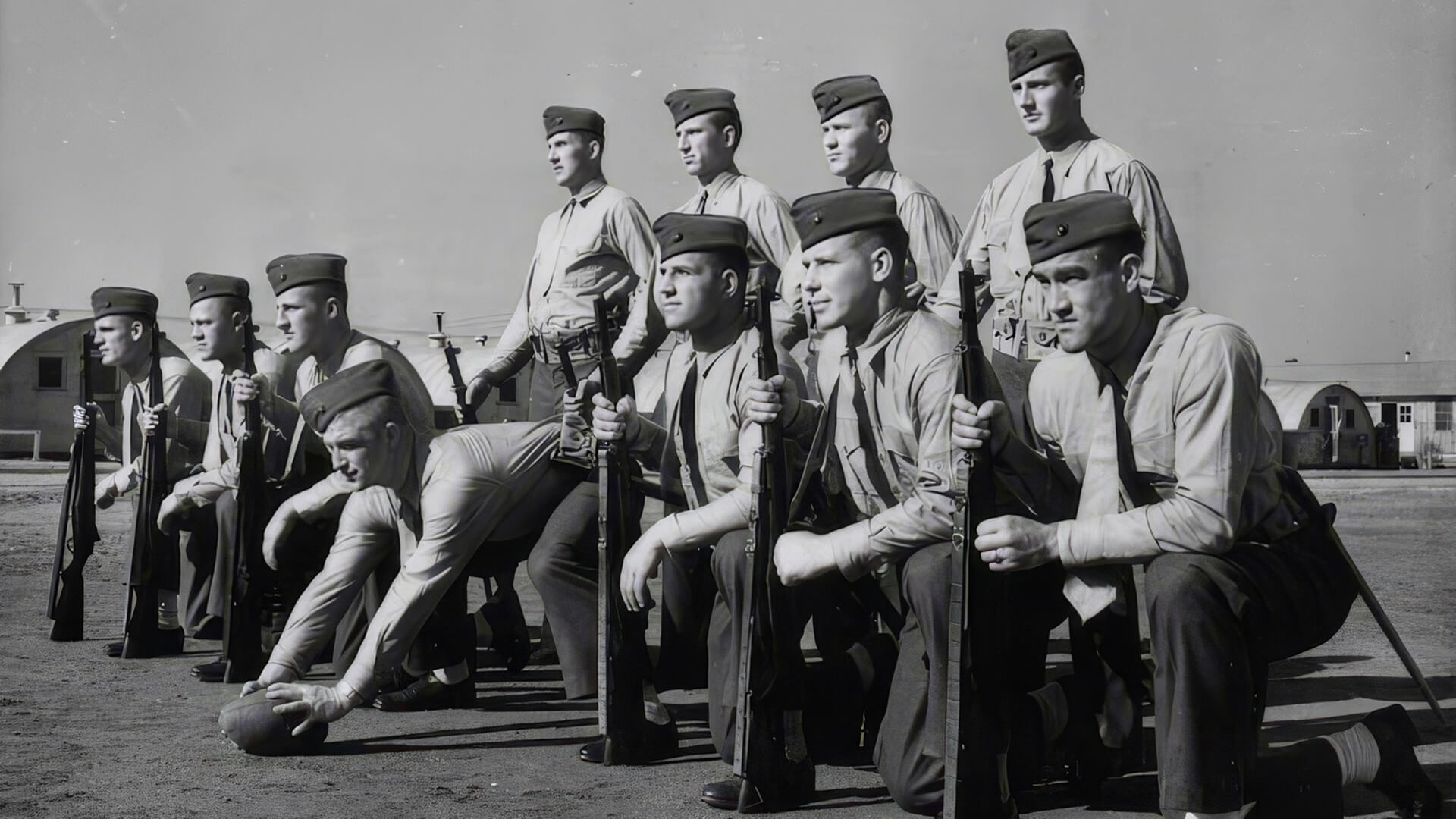 Tony Butkovich and a group of Marine trainees, , who had all been college football players, line up in a simulated football formation while in military uniform at Parris Island in South Carolina. 